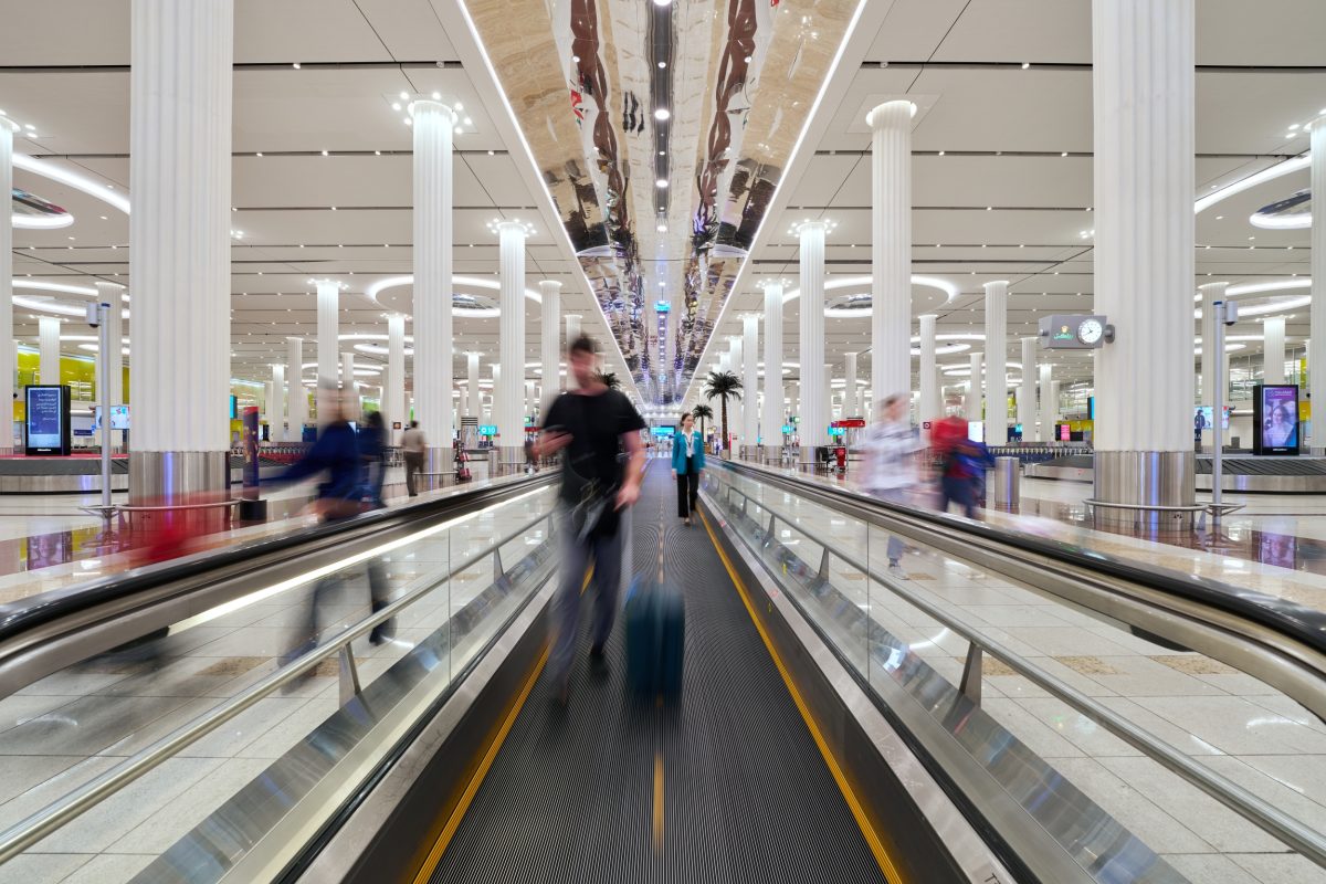 Empty airport terminal with escalators and few travelers amid sparse activity