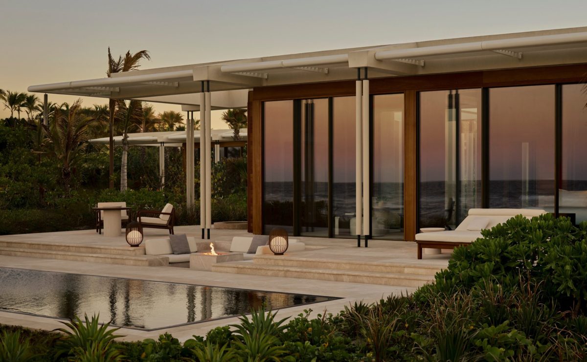Modern luxury villa with wooden doors overlooking the ocean at sunset in Baja California Sur