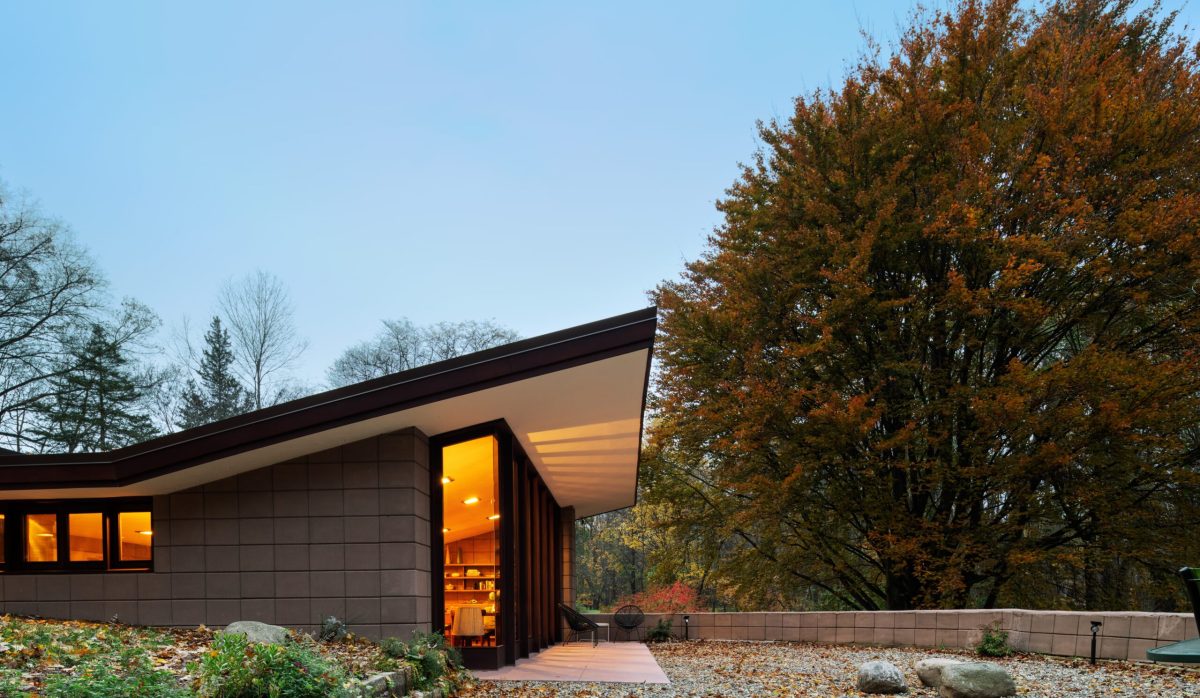 Modern minimalist cabin with warm lighting nestled among autumn trees