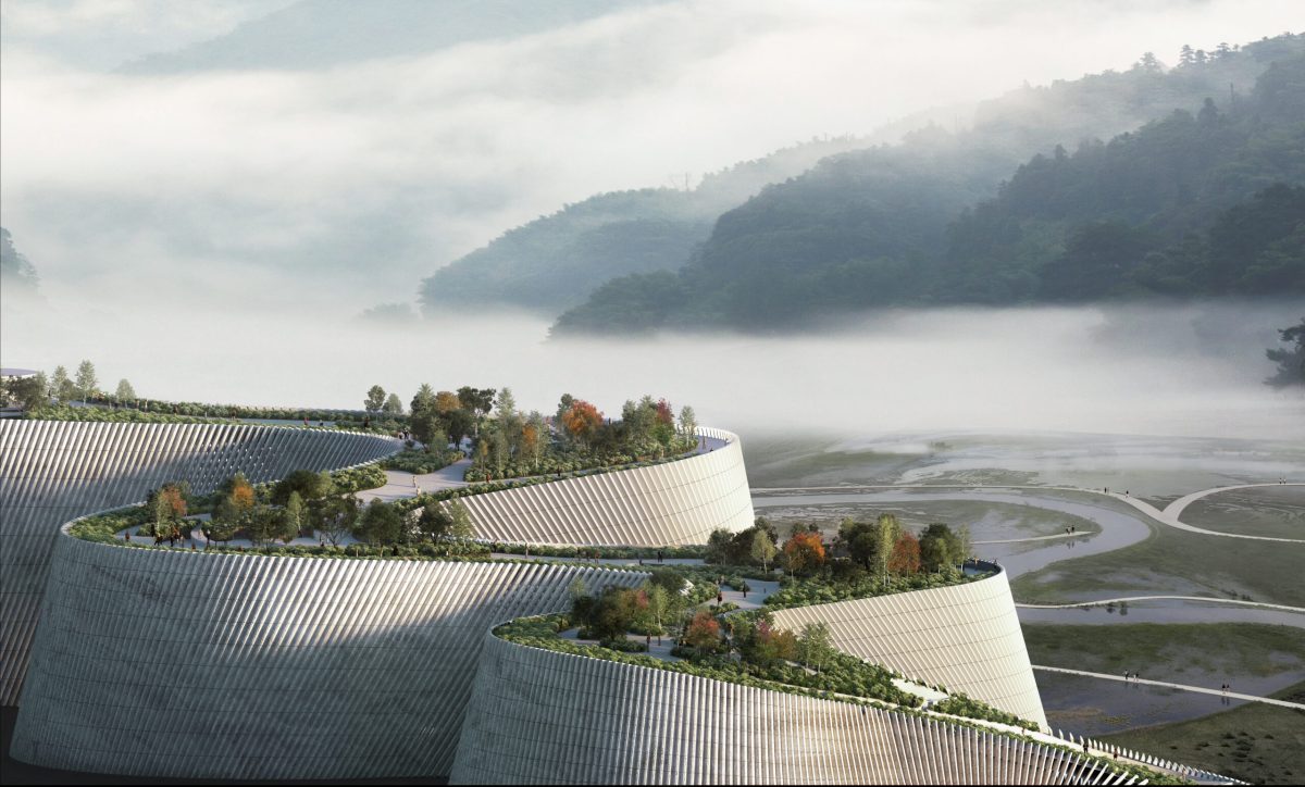 Modern museum building with green roofs overlooking misty lake and forested mountains