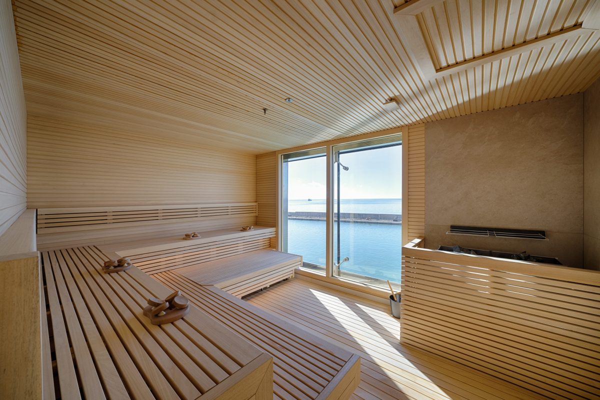 Modern sauna with wooden interior and panoramic ocean views through floor-to-ceiling windows