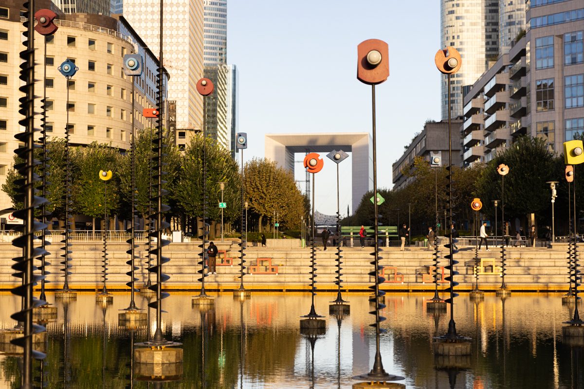 Modern waterfront plaza with orange sculptures and reflective water in contemporary Paris