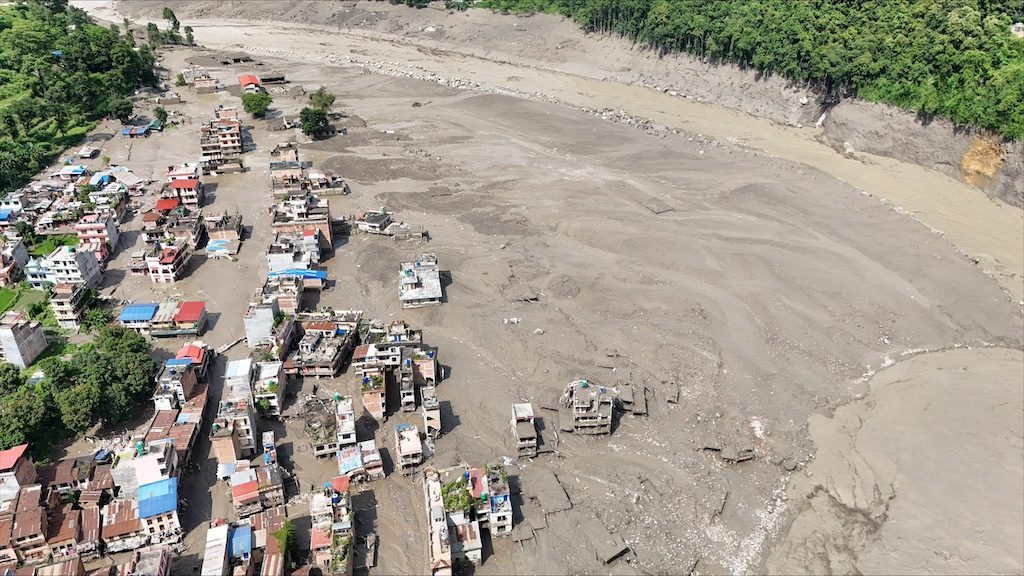 Aerial view of flood-damaged village in Nepal with muddy waters and scattered buildings