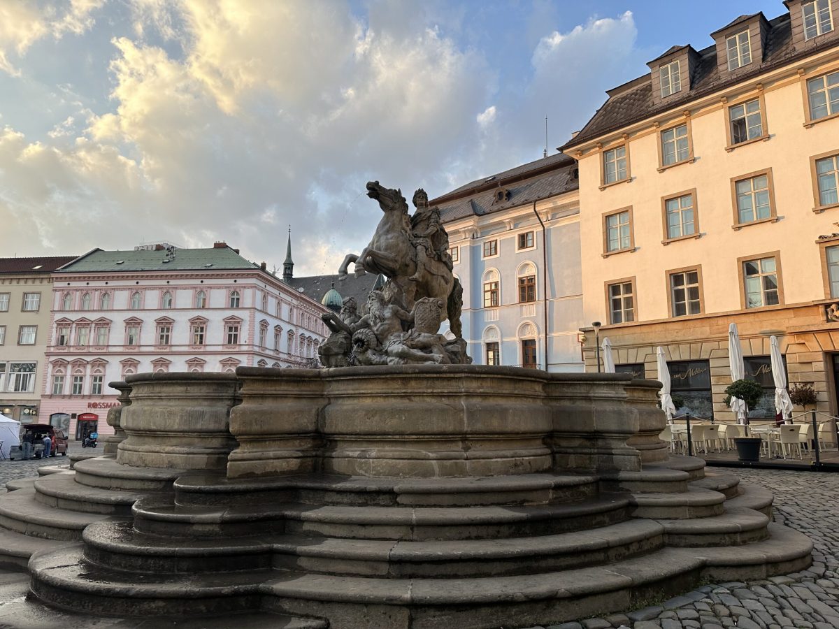 Ornate fountain with sculpture in historic Olomouc square surrounded by colorful baroque buildings