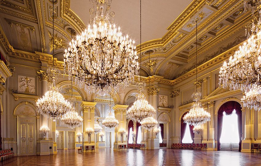 Ornate golden ballroom with crystal chandeliers and polished marble floors