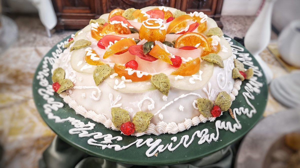 Ornate Sicilian cake decorated with colorful candied fruits and cream
