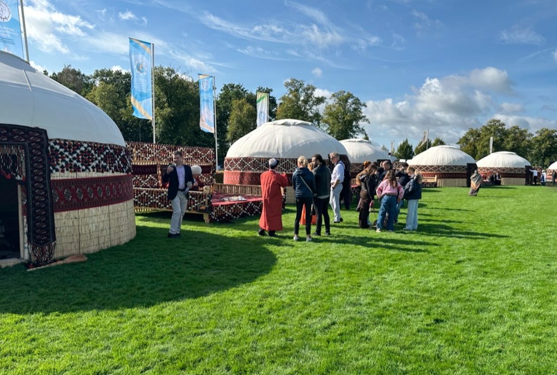 Outdoor festival grounds with white dome tents and visitors on green lawn