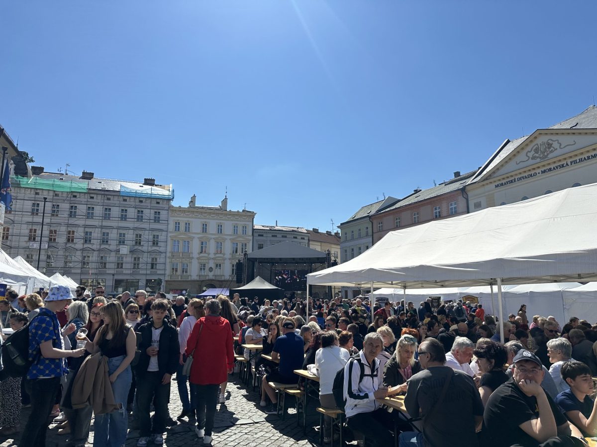 Outdoor market or festival in Olomouc's main square with crowds and white tents