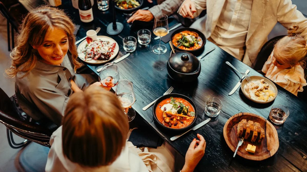 Overhead view of friends sharing a meal at a table with various dishes and drinks