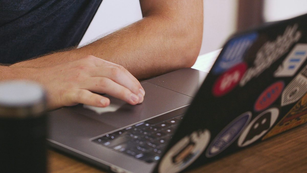 Person's hand on laptop keyboard at desk