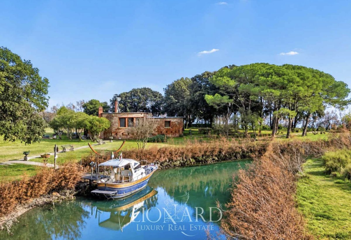 Private island in Venice Lagoon with historic brick building and tree-lined waterfront