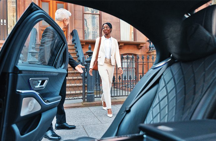 Professional man in white suit stepping into luxury vehicle with open door