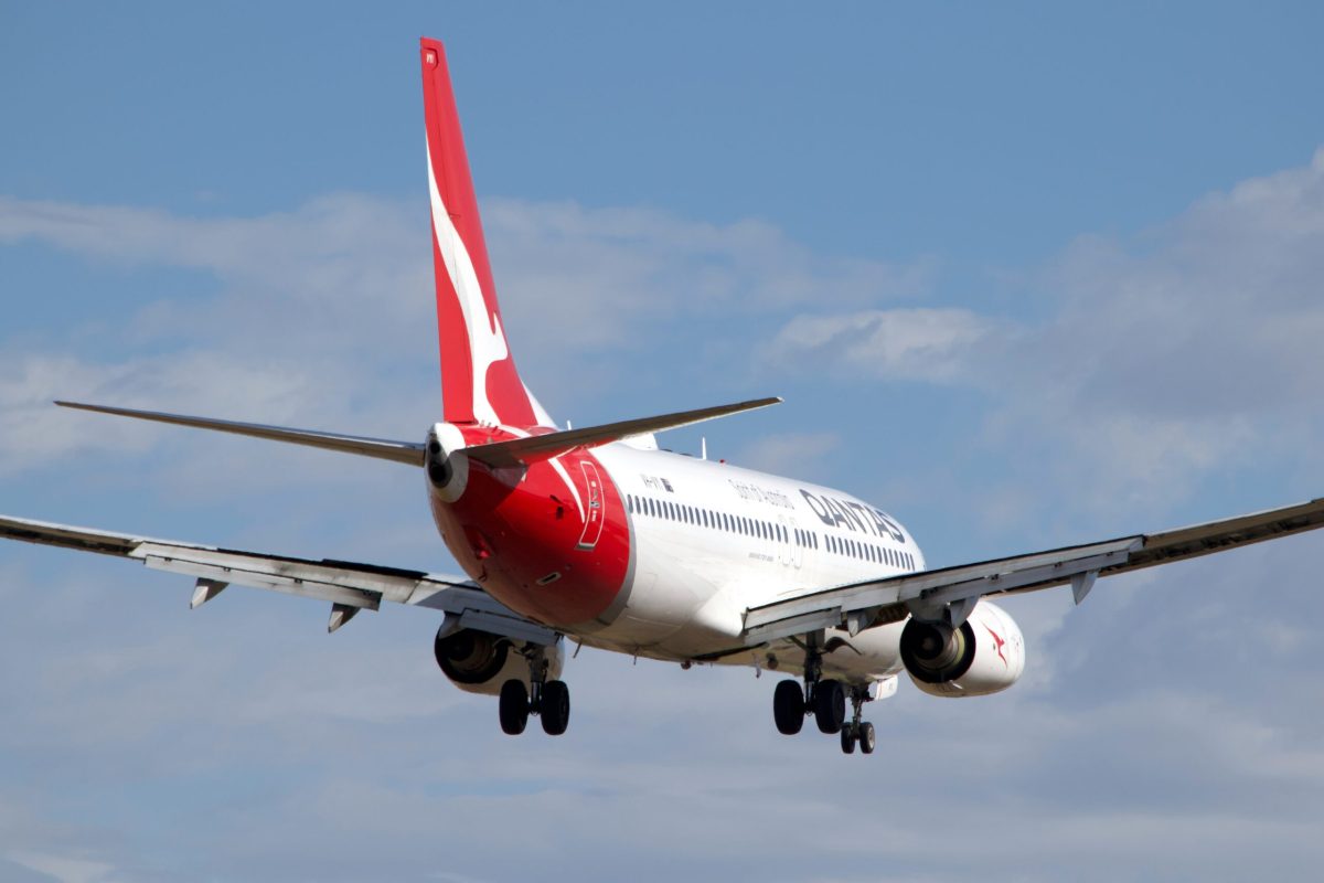 Qantas Boeing 737 aircraft in flight against blue sky with white clouds