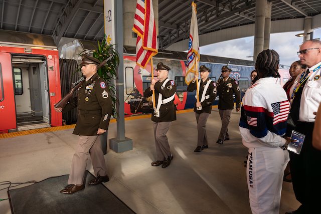 Veterans and officials gather inside a Brightline Freedom Express coach during a patriotic celebration event