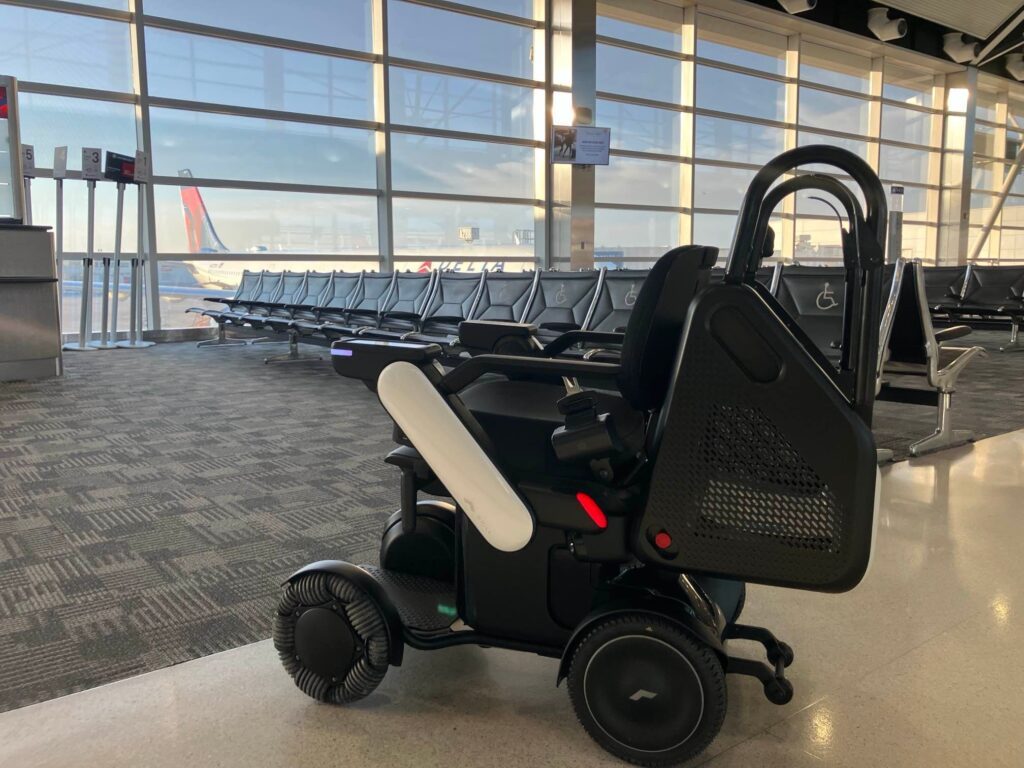 Self-driving robotic wheelchair in an airport terminal with seating and windows in background