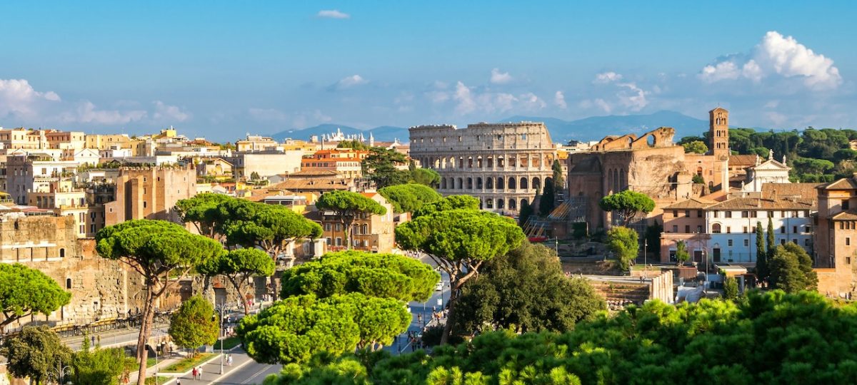Rome skyline with the Colosseum visible among green trees and historic buildings