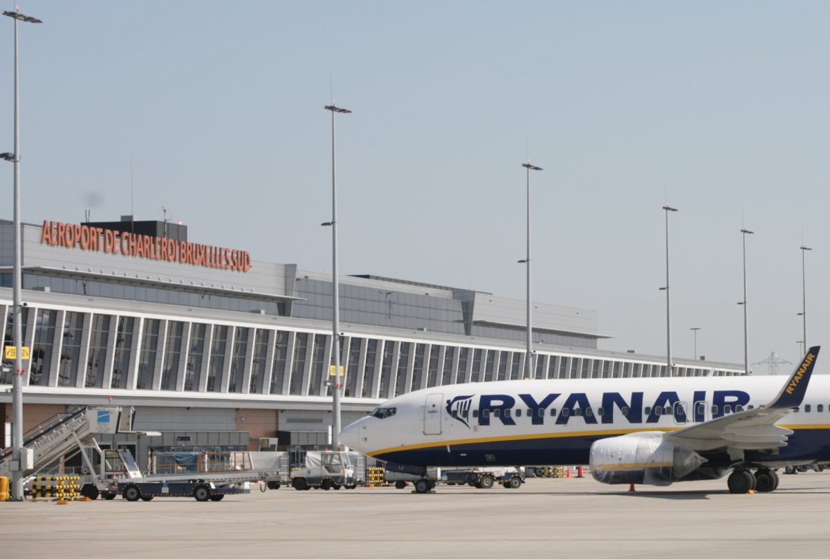 Ryanair aircraft parked at Charleroi Airport terminal with ground vehicles