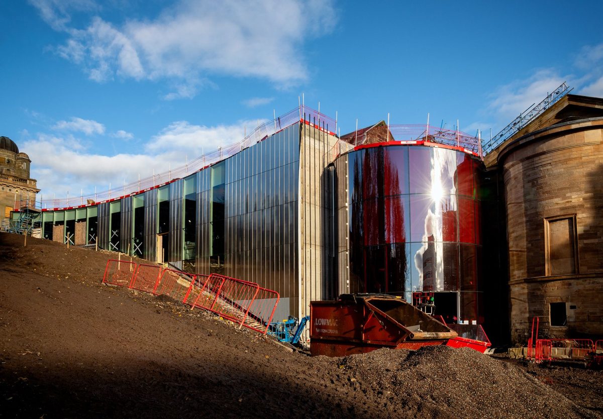 Paisley Museum under construction showing modern red-glass facade alongside historic stone buildings