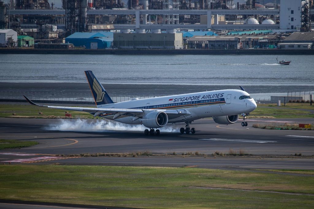 Singapore Airlines Airbus A350 landing on wet runway with city skyline behind