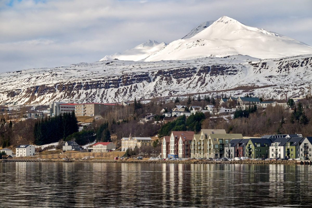 Snow-capped mountain overlooking colorful waterfront buildings in Akureyri, Iceland