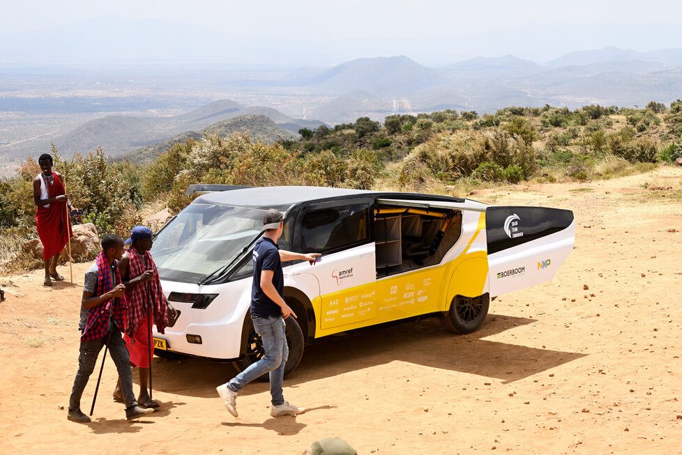 Solar-powered ambulance on dusty mountain terrain with Maasai people nearby
