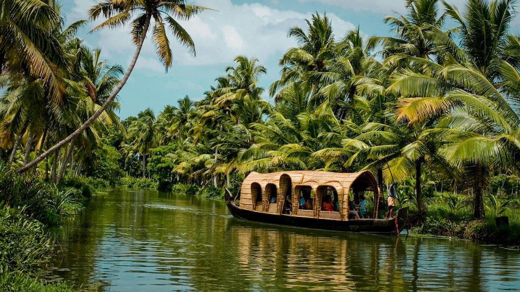 Traditional houseboat on Kerala backwaters surrounded by lush palm trees and green vegetation