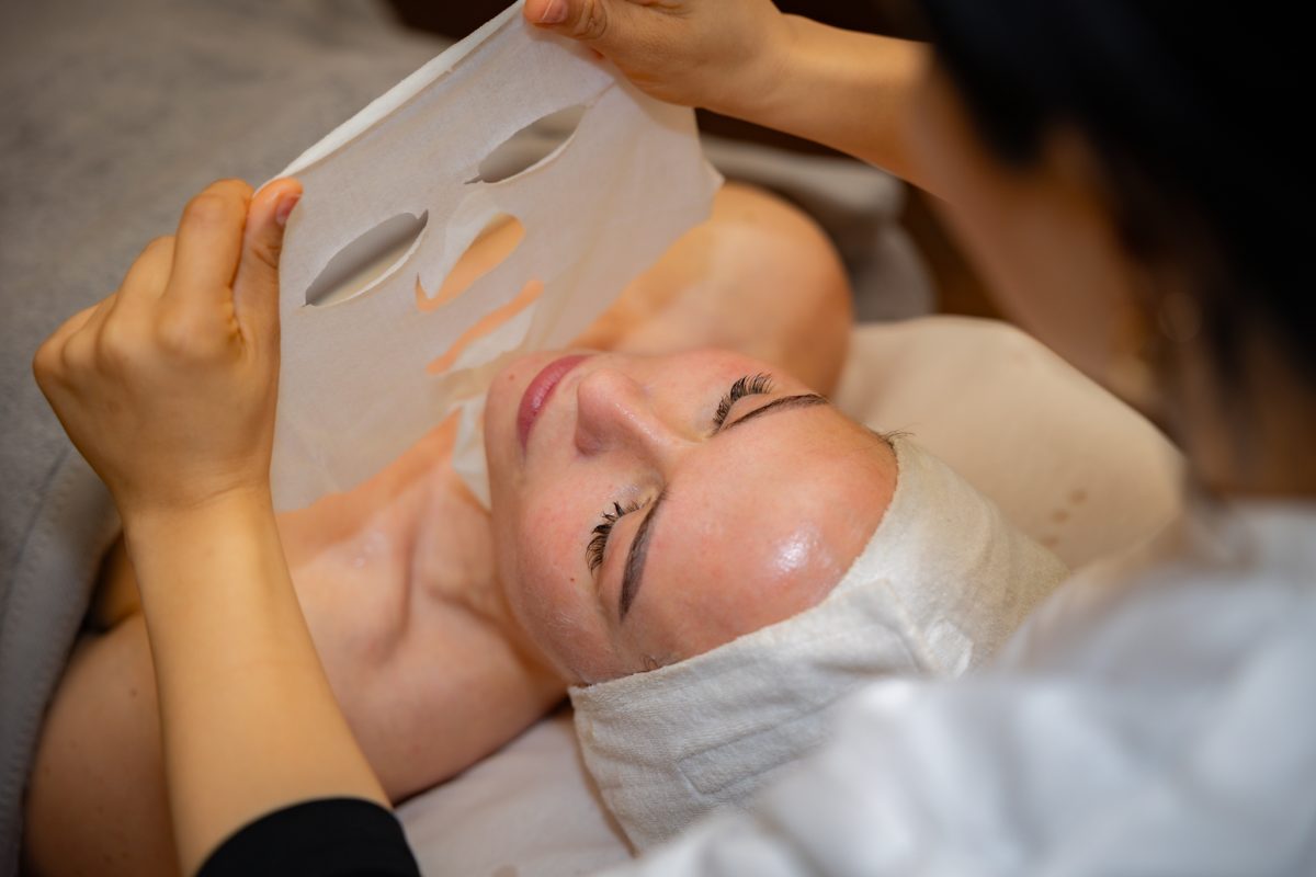 Spa therapist applying facial treatment to relaxed client during wellness ritual
