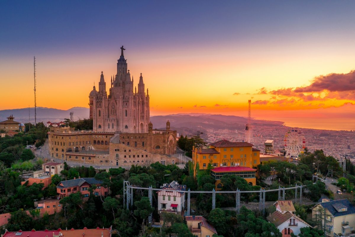 Ornate white cathedral with spires at golden sunset overlooking Spanish city landscape