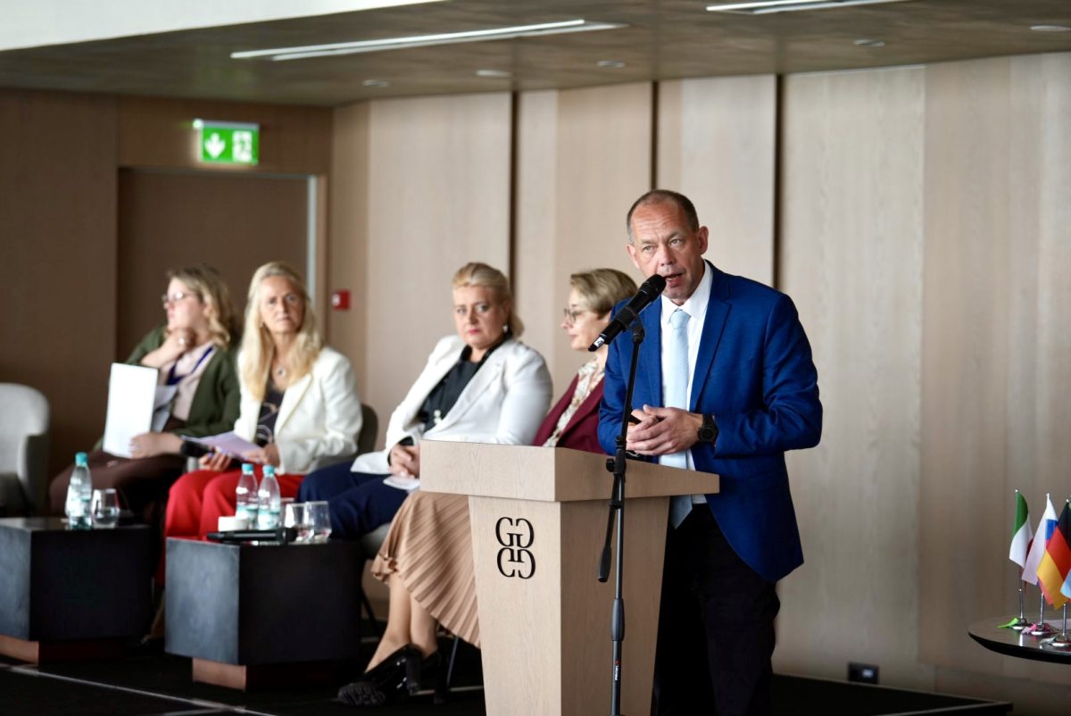 Speaker at podium during HEALTHXCHANGE Summit 2026 in Varna with panel members seated