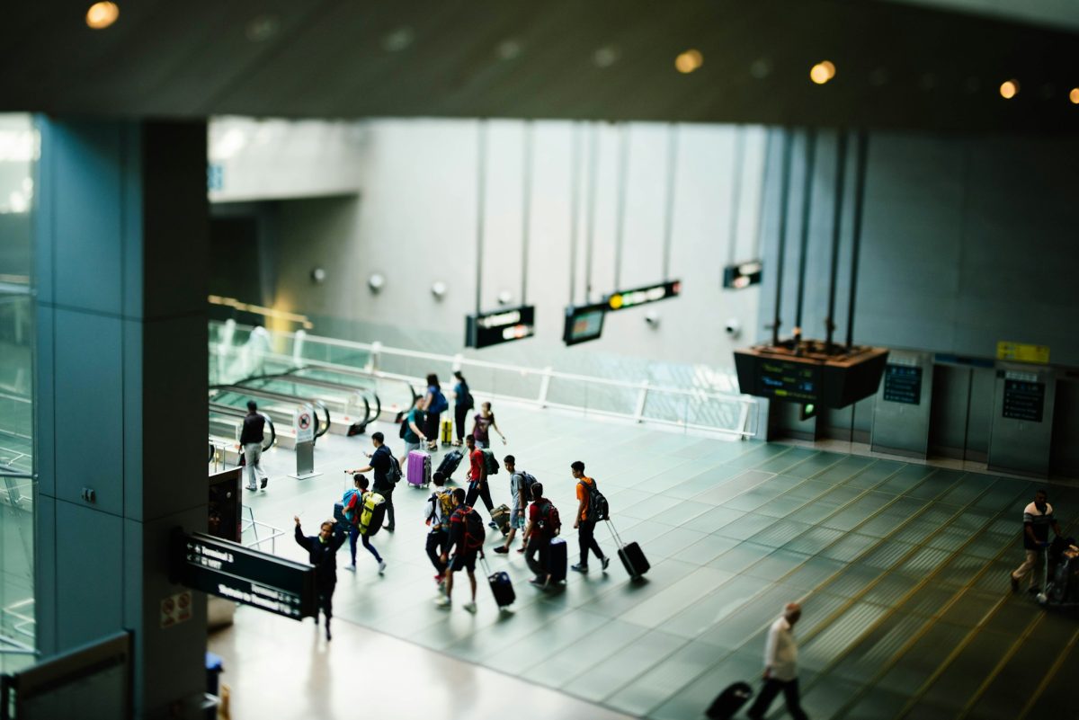 Busy airport terminal with travelers walking across a modern tiled floor