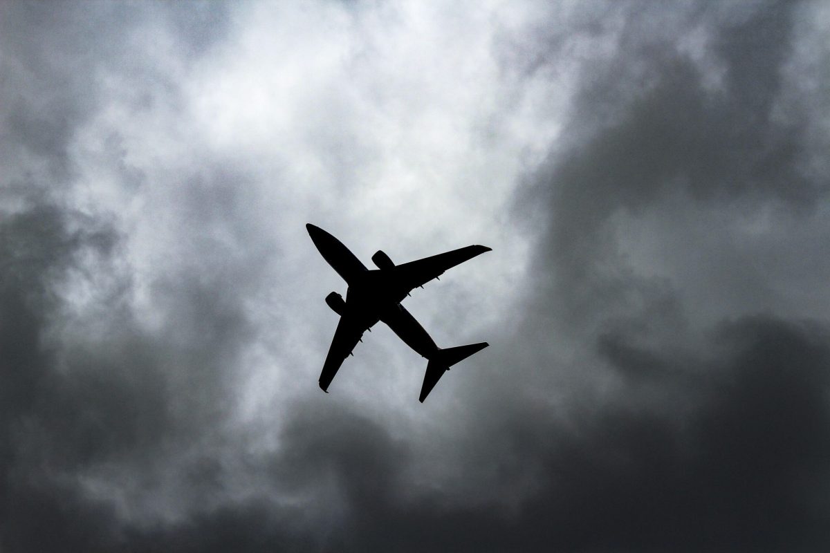 Silhouette of airplane against dark, stormy clouds