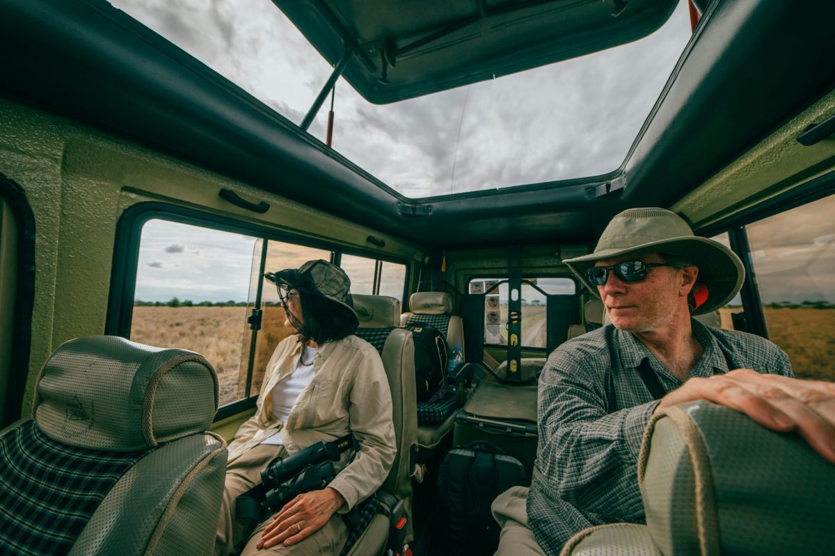 Couple on safari in Tanzania, looking out from a safari vehicle's open roof.