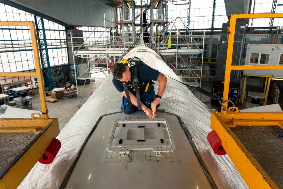 Technician installing Starlink antenna on Lufthansa aircraft fuselage