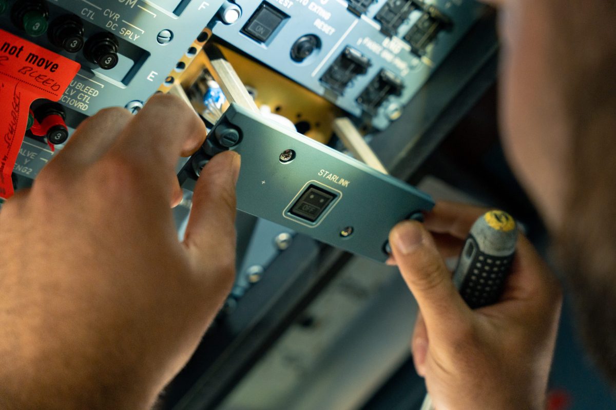 Technician installing Starlink Wi-Fi equipment in aircraft cabin