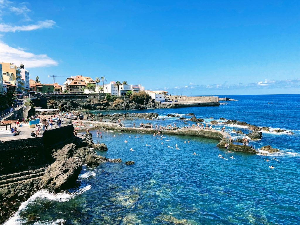 Coastal cliffs and turquoise waters with beachfront buildings in Tenerife