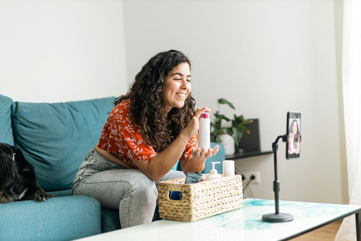 Woman recording content on smartphone with microphone setup at home