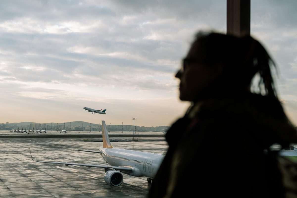 Silhouetted traveler watches a plane take off at dusk.