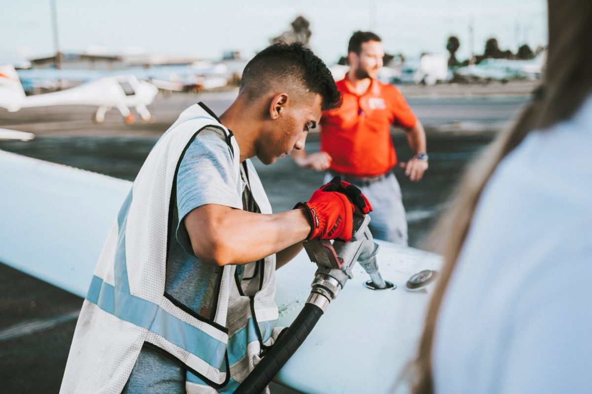Workers in safety gear inspecting aircraft during airport operations