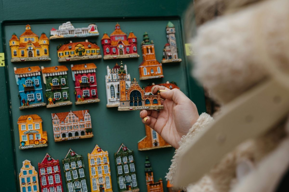 Hand selecting a miniature building magnet from a display of colorful souvenirs.