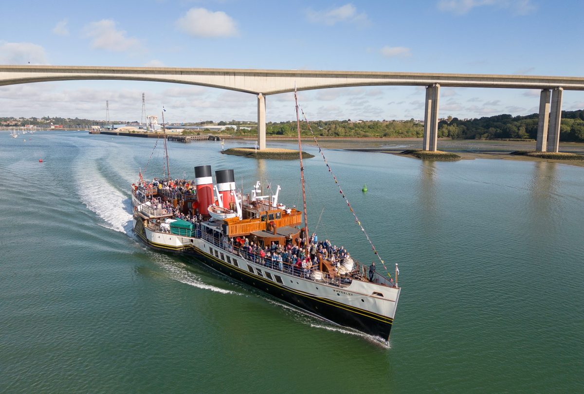 The Waverley paddle steamer sails on a bright day with a bridge in the background.