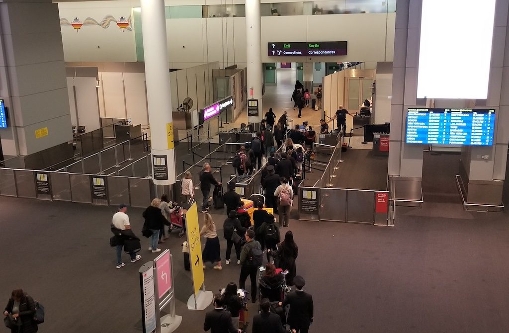 Busy airport terminal with crowds of travelers queuing at security checkpoints