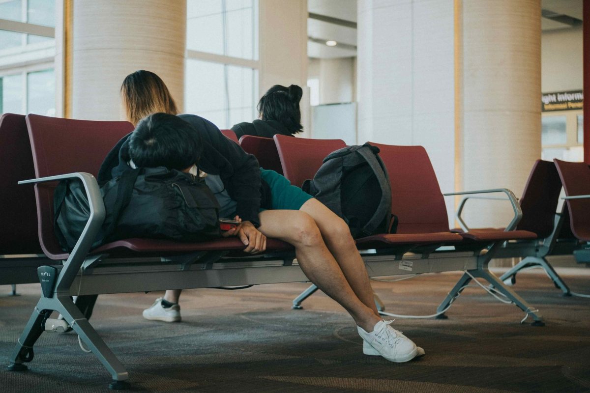 Traveler slumped in an airport chair, looking tired.