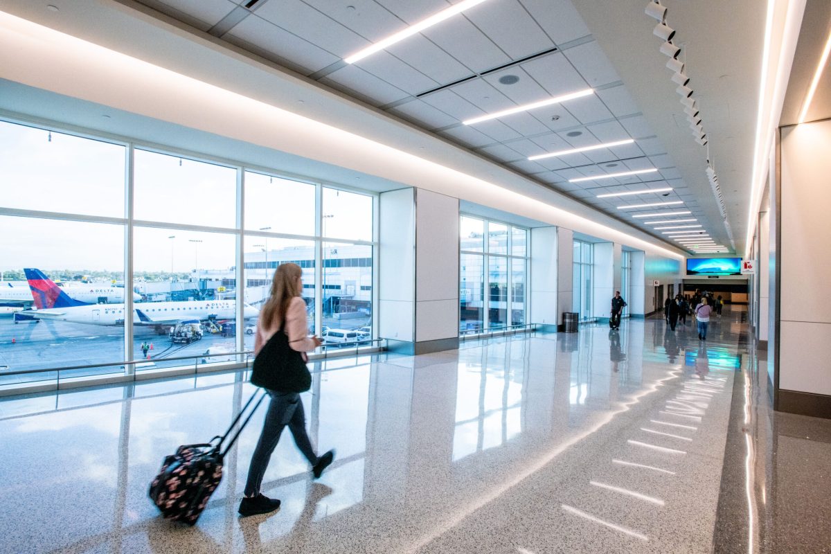 Traveler with rolling luggage walking through modern airport terminal