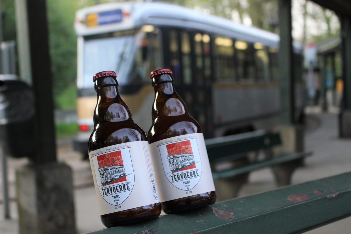 Two bottles of Tervoerke beer displayed on a table with a tram in the background