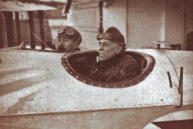 Two pilots in vintage aircraft cockpit with goggles and leather jackets