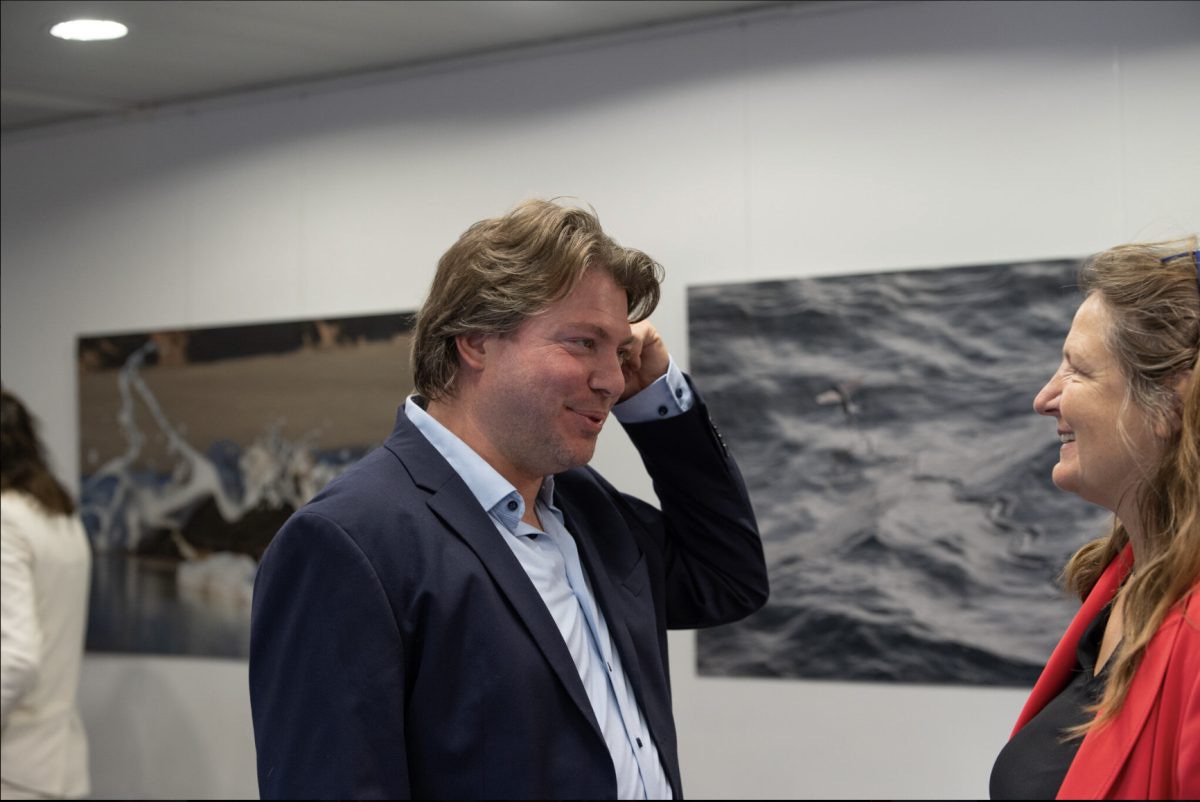 Two professionals in discussion at a climate conference, with ocean imagery displayed on wall behind them