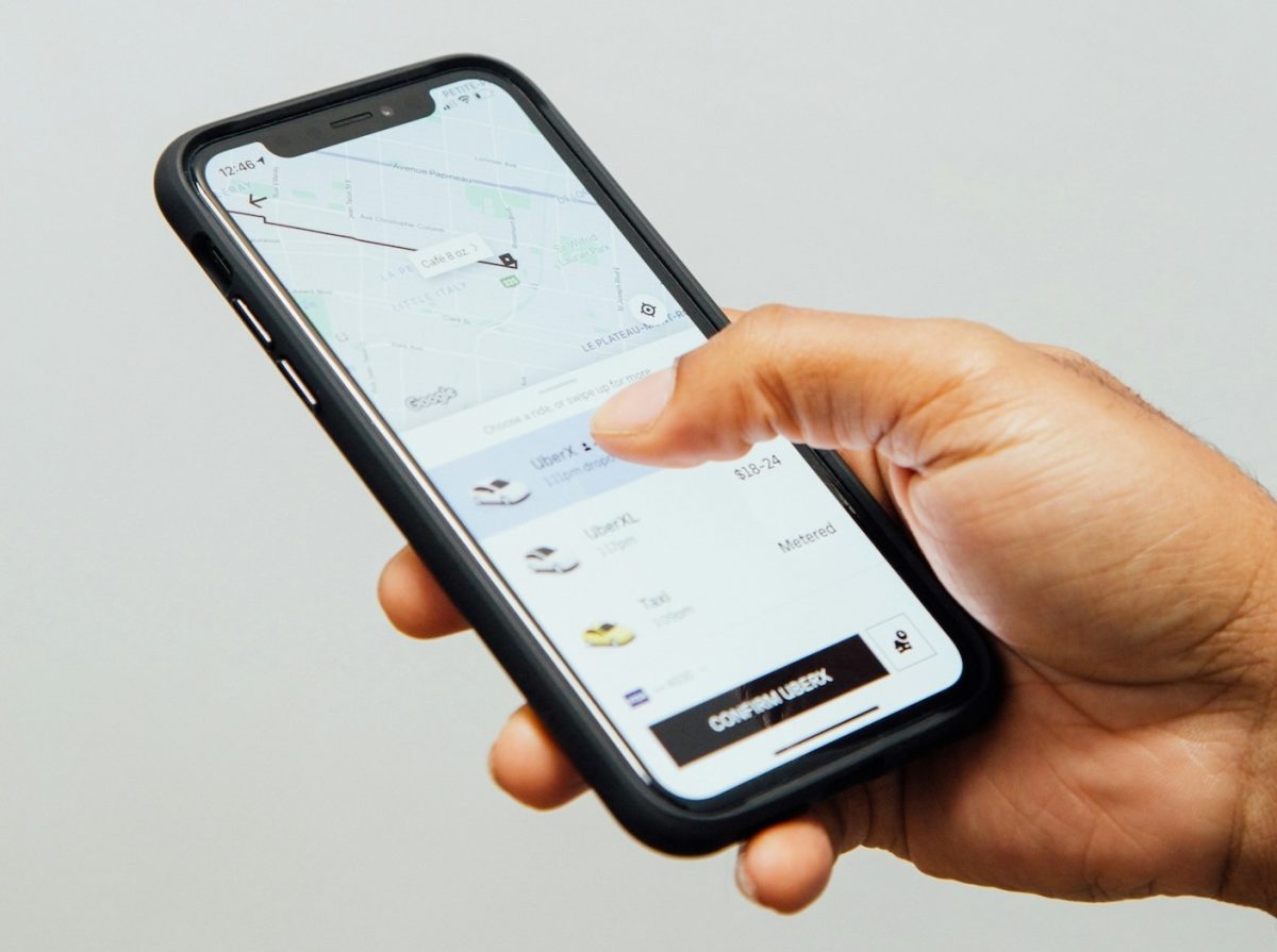 Hand holding smartphone displaying Uber app with map and booking options