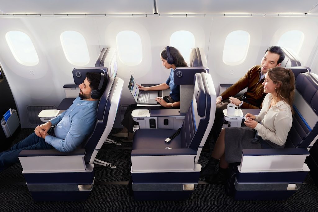 Passengers sitting in airplane seats with headphones and devices during flight
