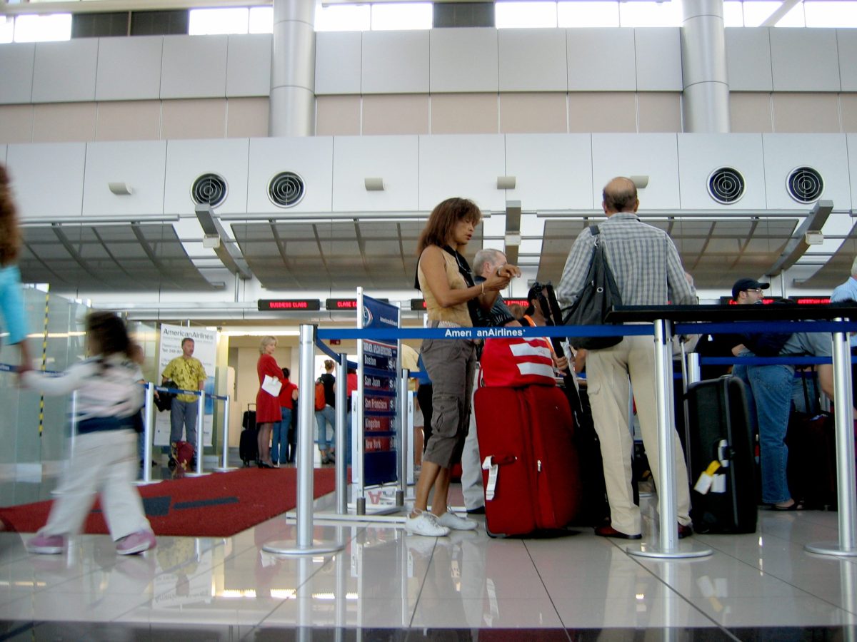 Passengers wait in line at airport check-in counter during busy travel day