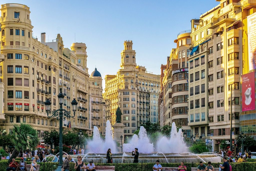Valencia's Plaza del Ayuntamiento with fountain and historic buildings in golden light